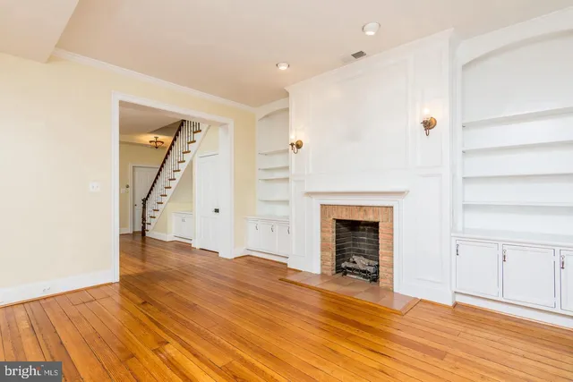 a view of an empty room with wooden floor fireplace and a window