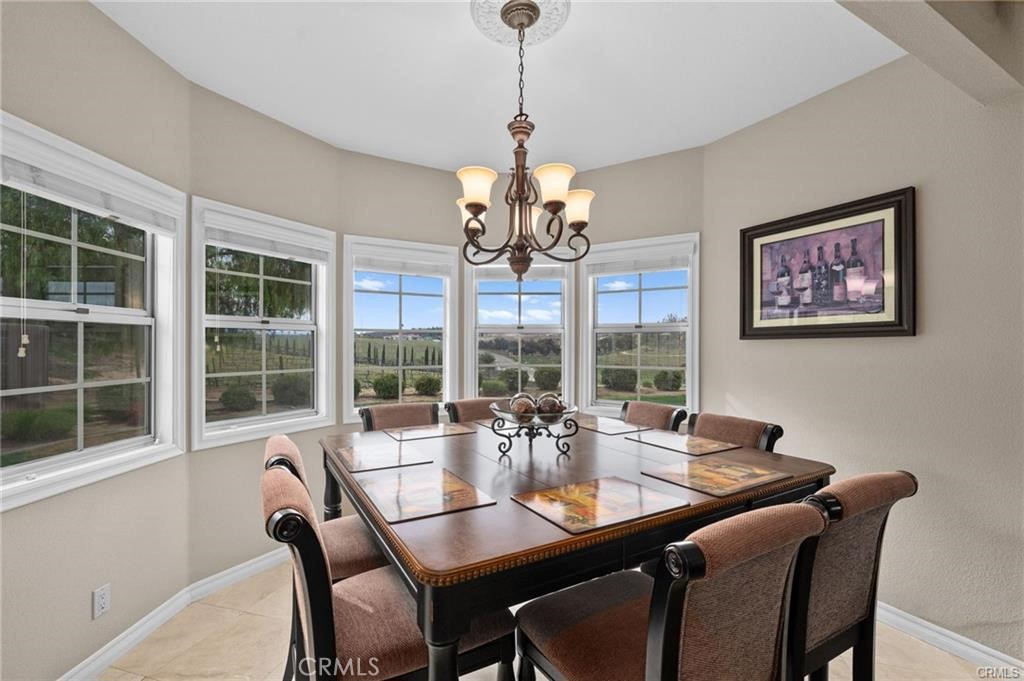 39581 Sperry Court Temecula, CA 92591 - Photo 19 of 63 a dining room with wooden floor a chandelier a wooden table and chairs