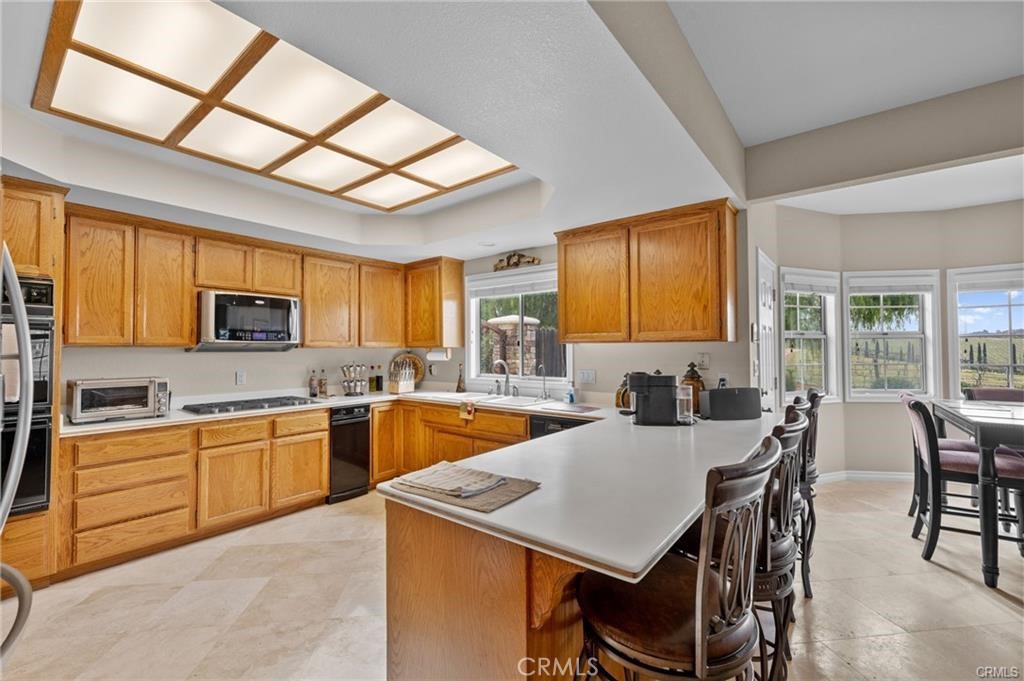39581 Sperry Court Temecula, CA 92591 - Photo 24 of 63 a kitchen with a stove a sink a dining table and chairs