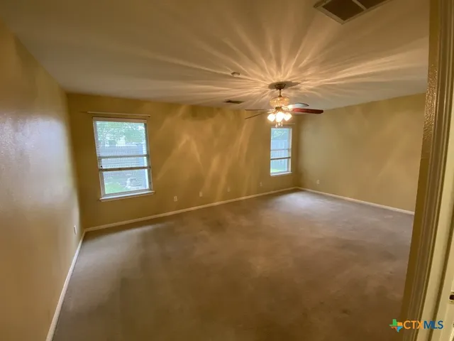 an empty room with windows and fan