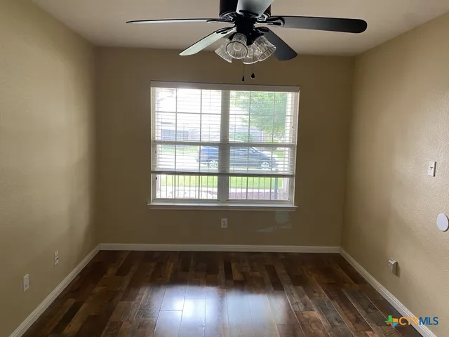 an empty room with wooden floor cabinet and windows