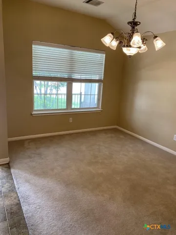 an empty room with a chandelier fan and windows