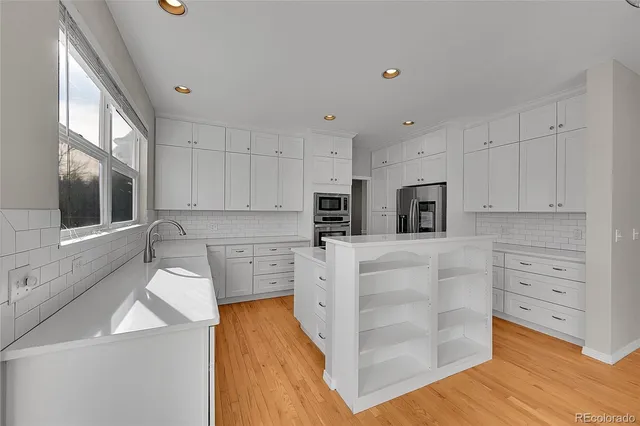 a kitchen with stainless steel appliances a refrigerator sink and white cabinets