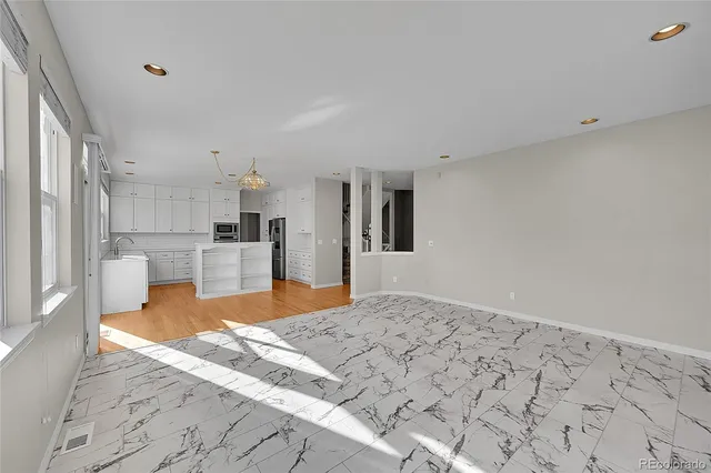a large white kitchen with kitchen island sink and refrigerator