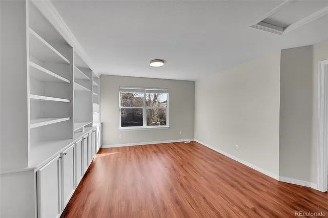 a view of an empty room with a window and wooden floor