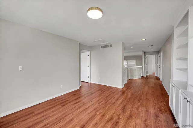 a view of empty room with wooden floor and fan