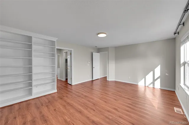 a view of an empty room with a window and wooden floor