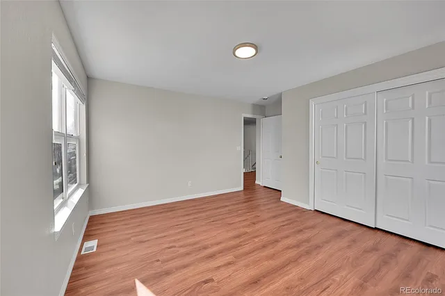 a view of an empty room with wooden floor and a window