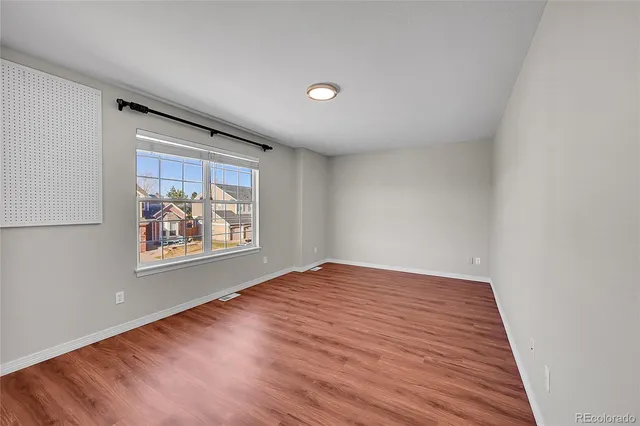 an empty room with wooden floor and window