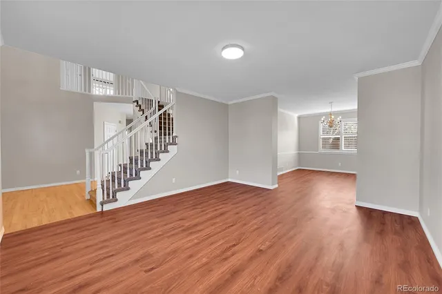a view of an empty room with wooden floor and stairs