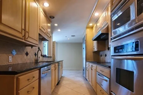 a kitchen with stainless steel appliances granite countertop a stove a sink and a microwave