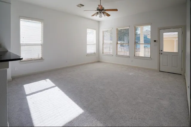 an empty room with windows and ceiling fan
