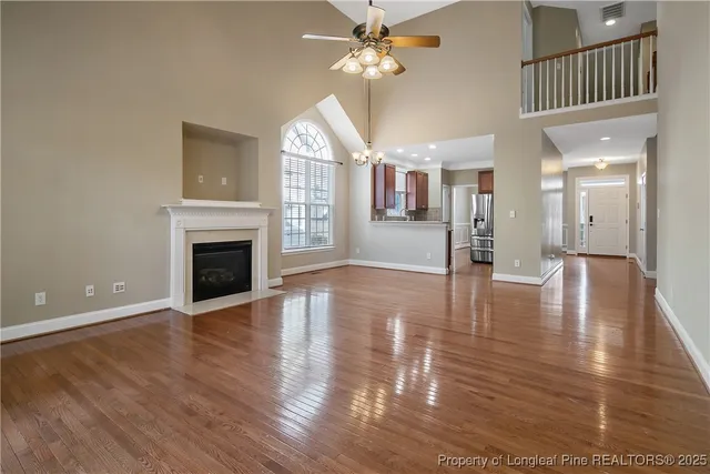 a view of a livingroom with wooden floor a ceiling fan and windows