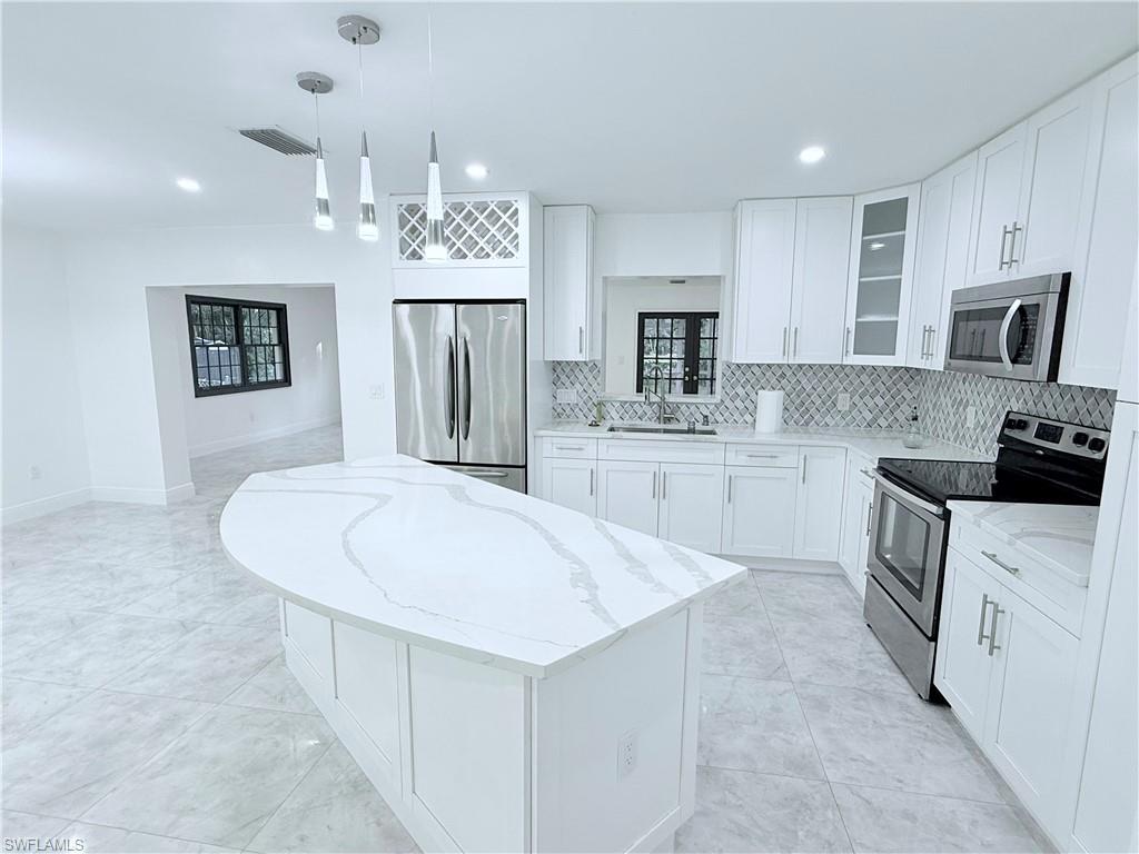 3330 13th Avenue Southwest Naples, FL 34117 - Photo 32 of 50 a kitchen with kitchen island a sink stove and refrigerator