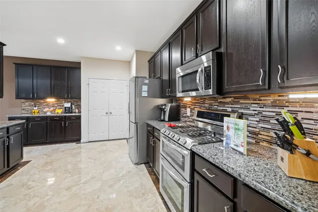 a kitchen with stainless steel appliances granite countertop a stove a sink and a refrigerator