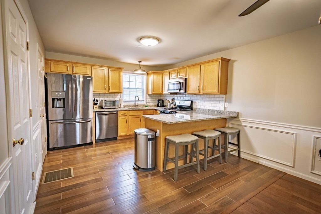 1084 Pine Street, Unit 2 Fall River, MA 02723 - Photo 6 of 22 a kitchen with stainless steel appliances granite countertop a stove a refrigerator a sink a dining table and chairs with wooden floor