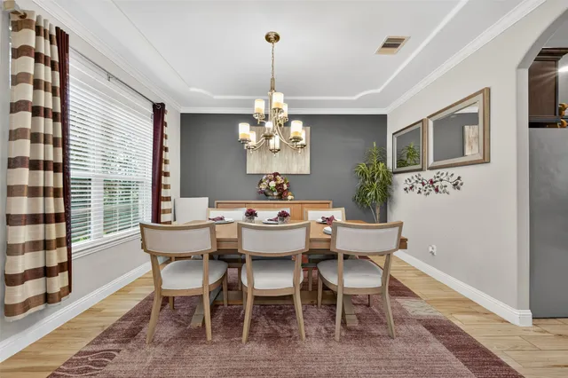 a dining room with wooden floor a chandelier a wooden table and chairs