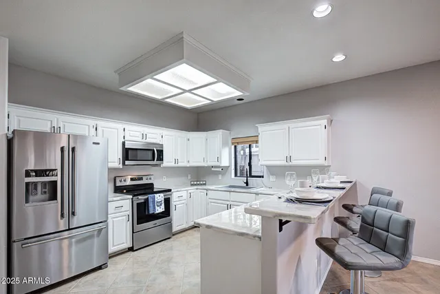 a kitchen with granite countertop white cabinets and white stainless steel appliances