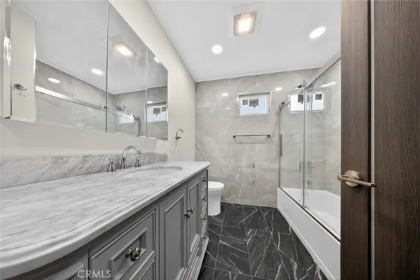 a bathroom with a granite countertop sink a mirror and a shower