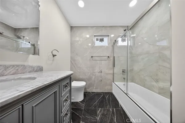 a bathroom with a granite countertop sink toilet and shower