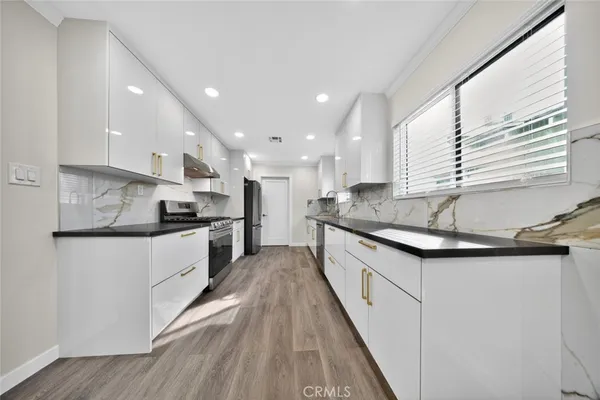 a kitchen with stainless steel appliances granite countertop a sink a stove and a refrigerator