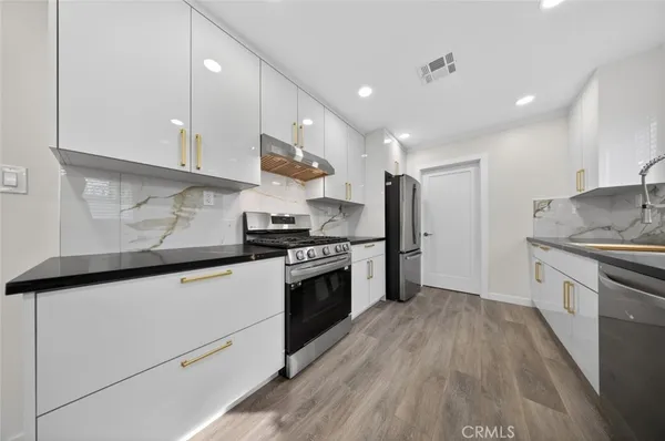 a kitchen with stainless steel appliances granite countertop a sink a stove and a refrigerator