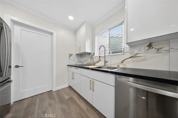 a kitchen with granite countertop a sink and a white wooden cabinets