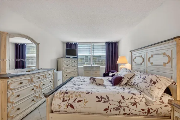 a bedroom with a large bed and a flat tv screen on dresser