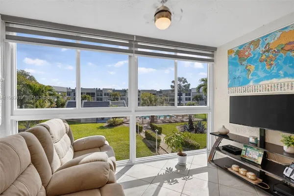 a living room with furniture a flat screen tv and a floor to ceiling window