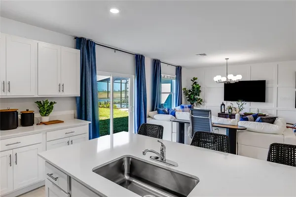 a kitchen with stainless steel appliances kitchen island granite countertop a refrigerator a stove a sink and white cabinets with wooden floor