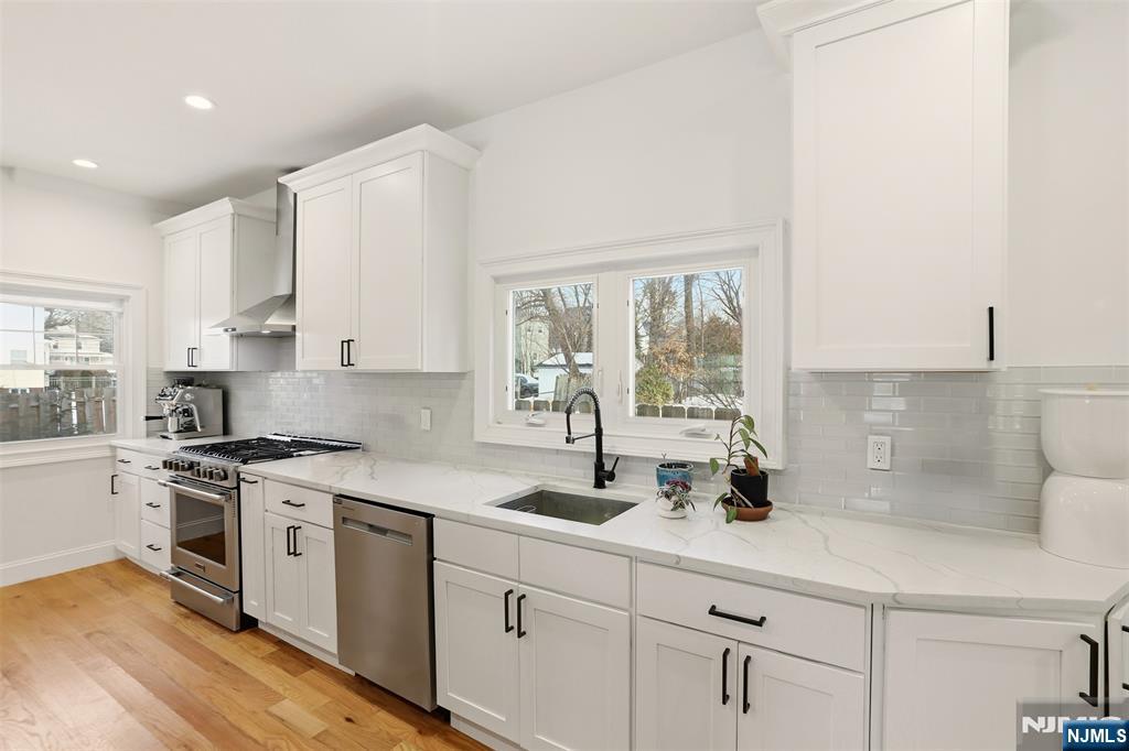 403 Lawn Ridge Road Orange, NJ 07050 - Photo 16 of 45 a kitchen with white cabinets a sink a stove and a window