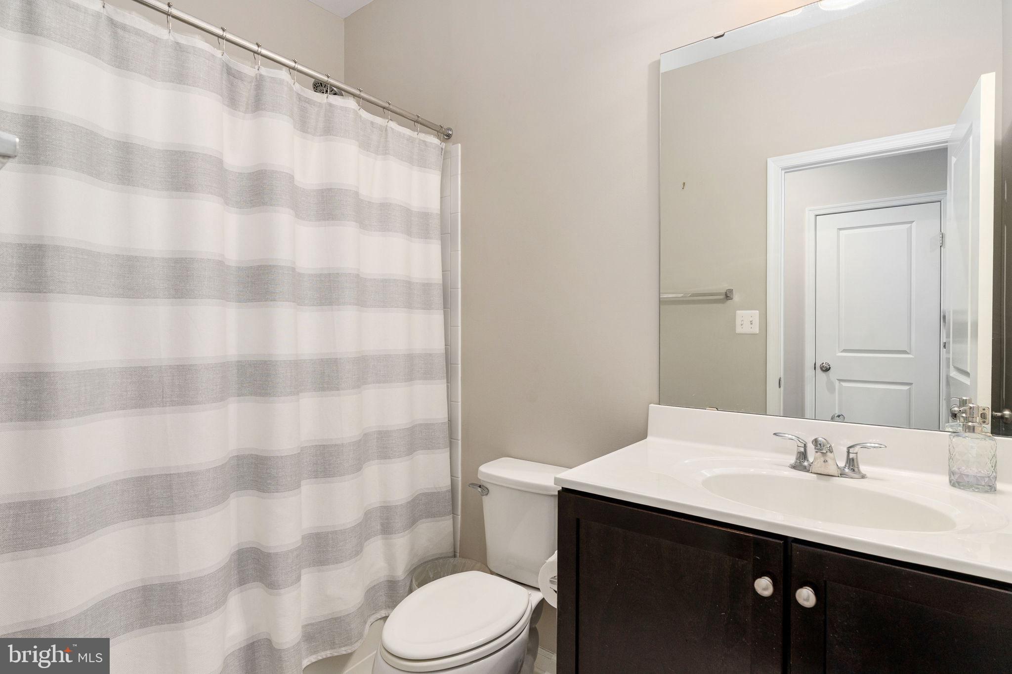 650 Aspen Road, Unit 108 Stafford, VA 22554 - Photo 8 of 30 a bathroom with a sink a toilet a mirror and shower curtain