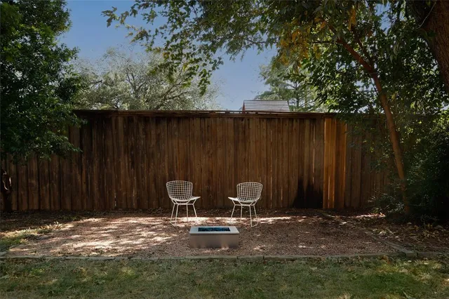 a backyard of a house with chairs and wooden fence