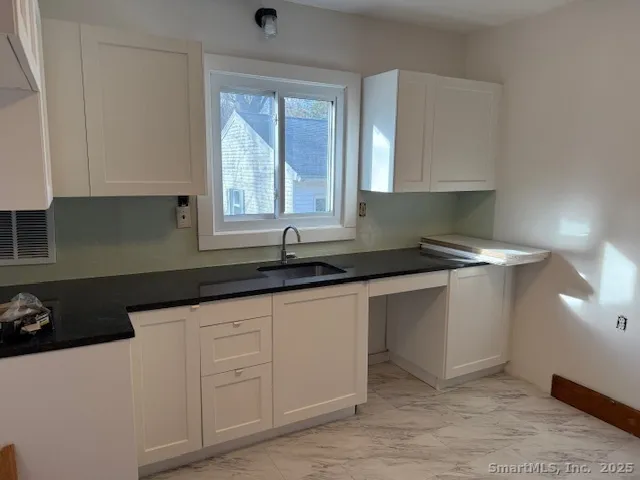 a kitchen with granite countertop white cabinets and sink