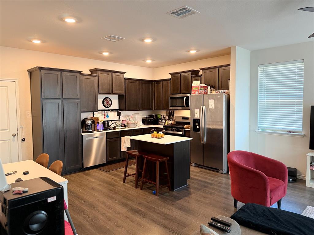2001 Juniper Pass Way Mesquite, TX 75149 - Photo 2 of 12 Kitchen with dark wood finish cabinetry, stainless steel appliances, dark wood-style floors, a center island, and a kitchen bar