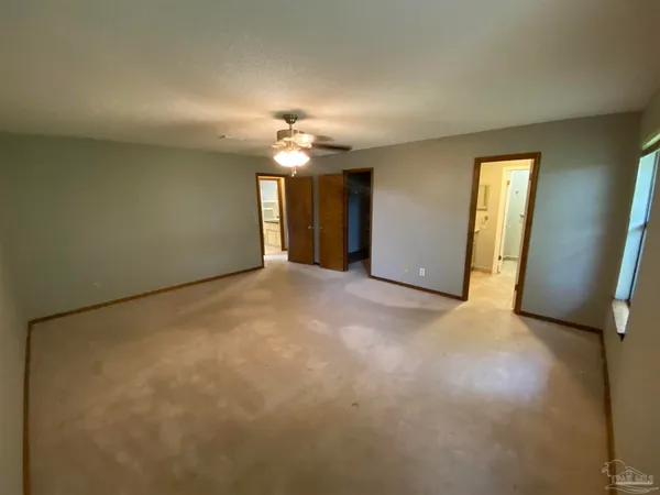 a view of an empty room with a chandelier fan