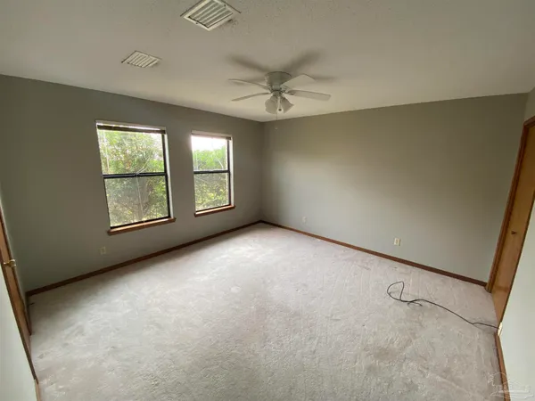 an empty room with windows and fan
