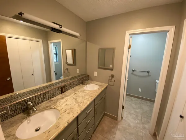 a bathroom with a granite countertop double vanity sink and mirror