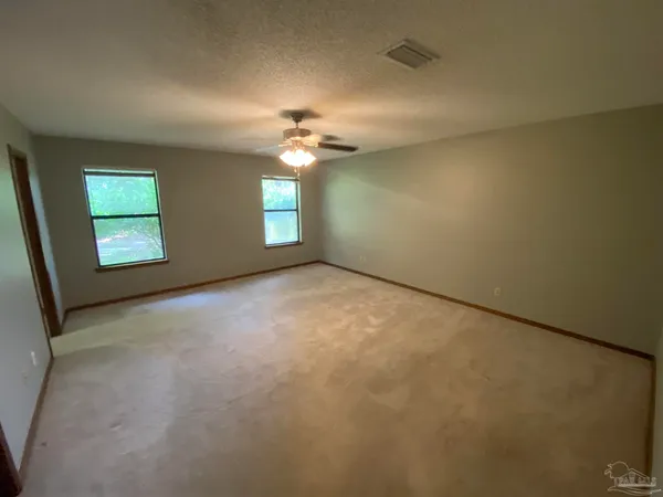 an empty room with windows and fan