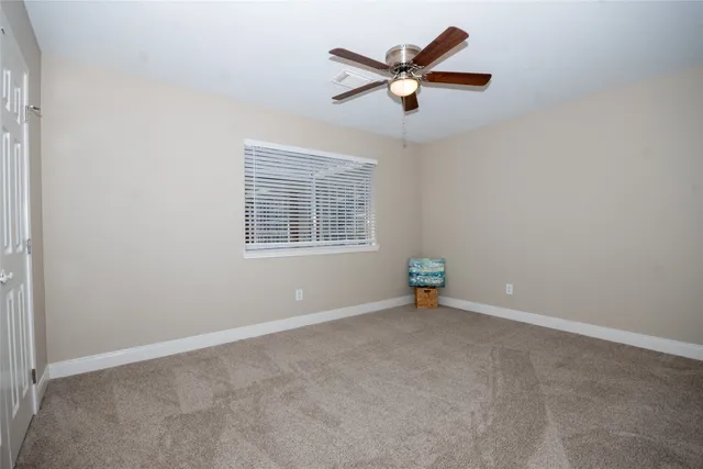 an empty room with ceiling fan and windows