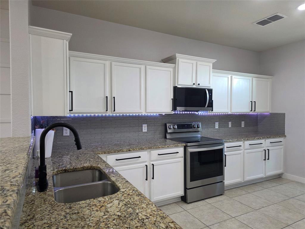 149 Ryan Street Anna, TX 75409 - Photo 10 of 38 a kitchen with stainless steel appliances granite countertop a sink stove and microwave