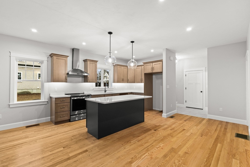 35 Leonard Street, Unit 3 Bridgewater, MA 02324 - Photo 6 of 29 a large kitchen with stainless steel appliances kitchen island granite countertop a stove a sink dishwasher and a refrigerator with wooden floor