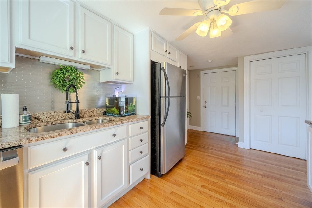 120 Goldsmith Street, Unit 4 Littleton, MA 01460 - Photo 16 of 26 a kitchen with stainless steel appliances granite countertop a refrigerator a sink dishwasher and white cabinets with wooden floor