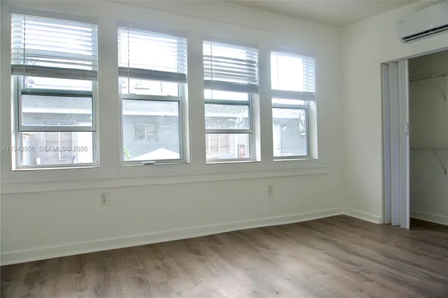 a view of an empty room with wooden floor and windows