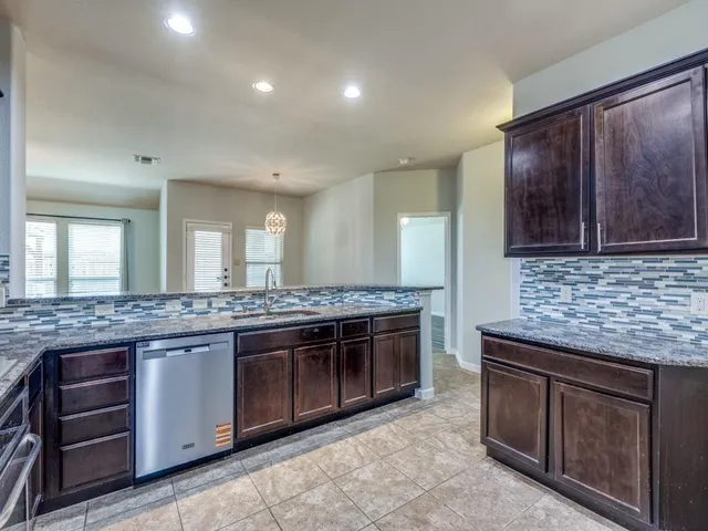 a kitchen with stainless steel appliances granite countertop wooden cabinets and a stove top oven