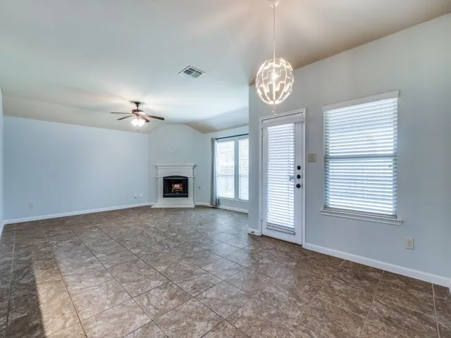 an empty room with windows and fireplace