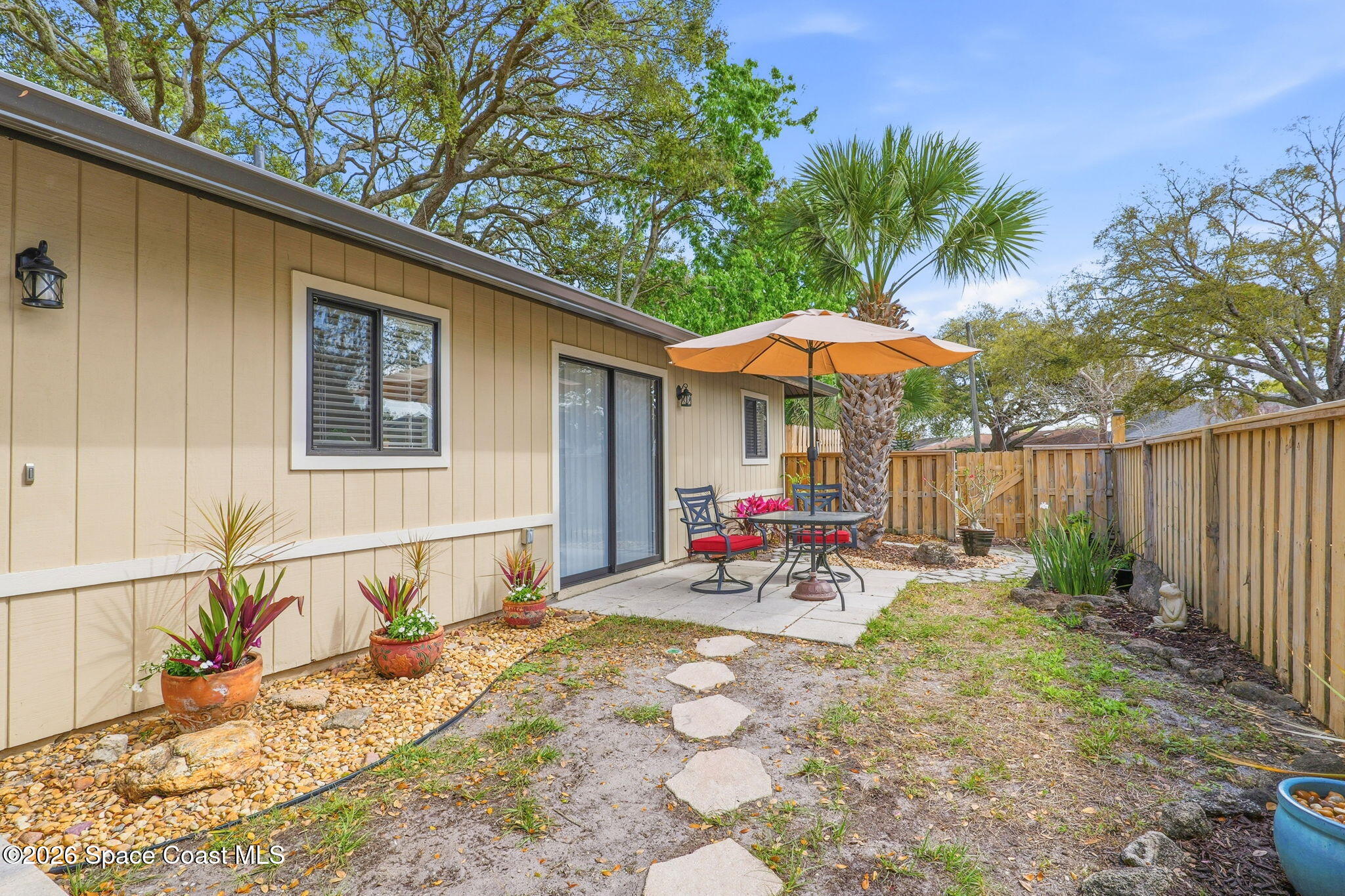 984 Bayberry Lane Rockledge, FL 32955 - Photo 3 of 39 a view of a patio with table and chairs under an umbrella with wooden fence