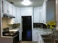 a kitchen with granite countertop a sink stove and refrigerator
