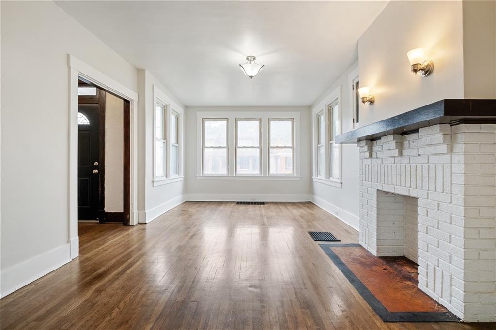 1306 Broadway Avenue McKees Rocks, PA 15136 - Photo 5 of 33 an empty room with wooden floor fireplace and windows