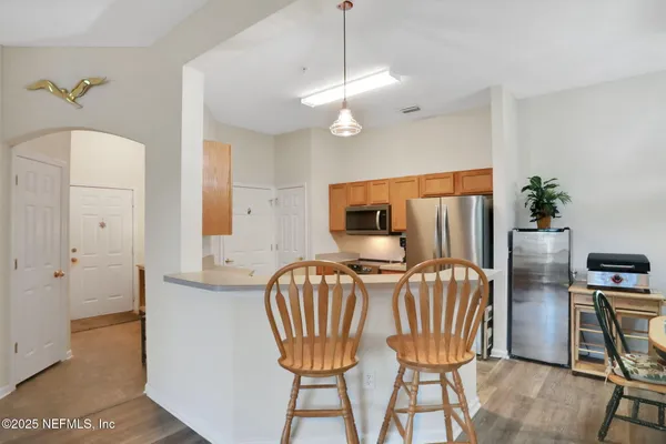 a kitchen with stainless steel appliances granite countertop a refrigerator a stove and a sink with wooden floors